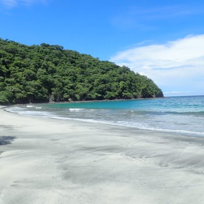 a sandy beach next to a body of water