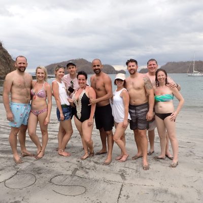 a group of people standing on a beach posing for the camera